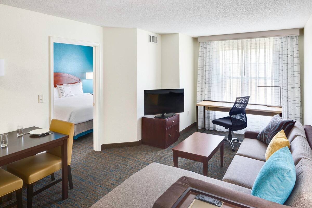 A hotel room with a bed, a television, a sofa, a desk, and a chair.