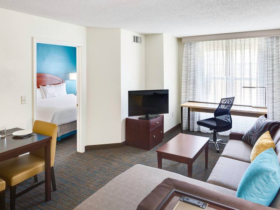 A hotel room with a bed, a television, a sofa, a desk, and a chair.