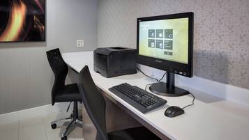 A modern office desk with a desktop computer, keyboard, mouse, and a printer.