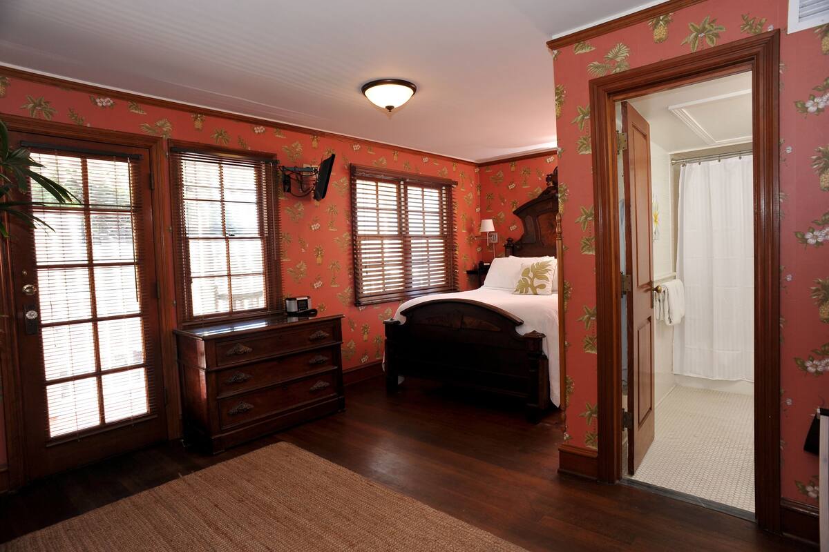 Une pièce comprenant un lit, une commode et une porte donnant sur une salle de bain.