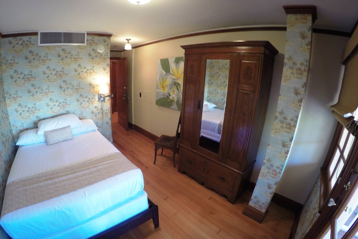 Une chambre avec un grand lit, une armoire en bois et un papier peint à motifs floraux.