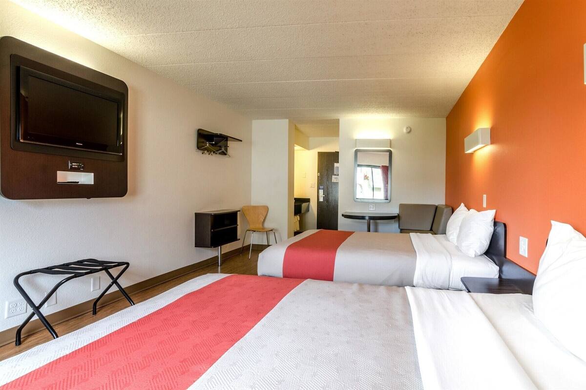 Une chambre d’hôtel avec deux lits, une télévision, un bureau et une chaise.