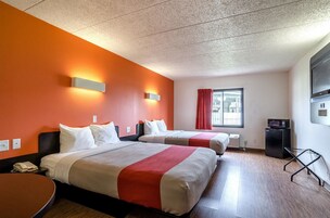 Habitación de hotel con dos camas, televisión, microondas y ventana con cortinas.