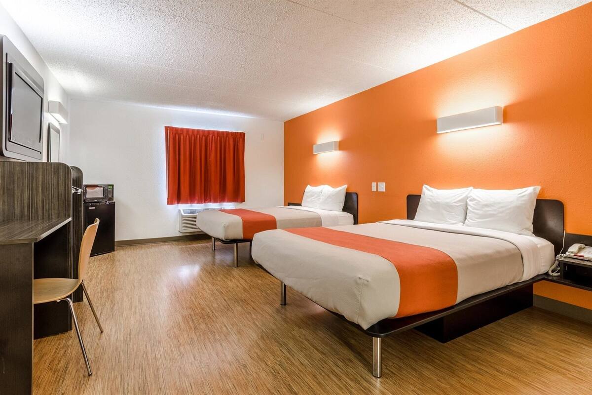 Une chambre d’hôtel avec deux lits, un bureau et une chaise.