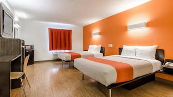 Quarto de hotel com duas camas, uma escrivaninha e uma cadeira.