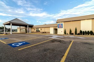 Un motel con estacionamiento techado, espacios reservados para discapacitados y un letrero que indica el número del motel.