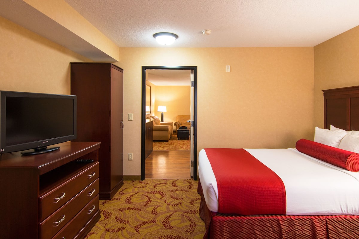 Une chambre d’hôtel comprenant un lit, une télévision, une commode et un couloir menant à une autre pièce.
