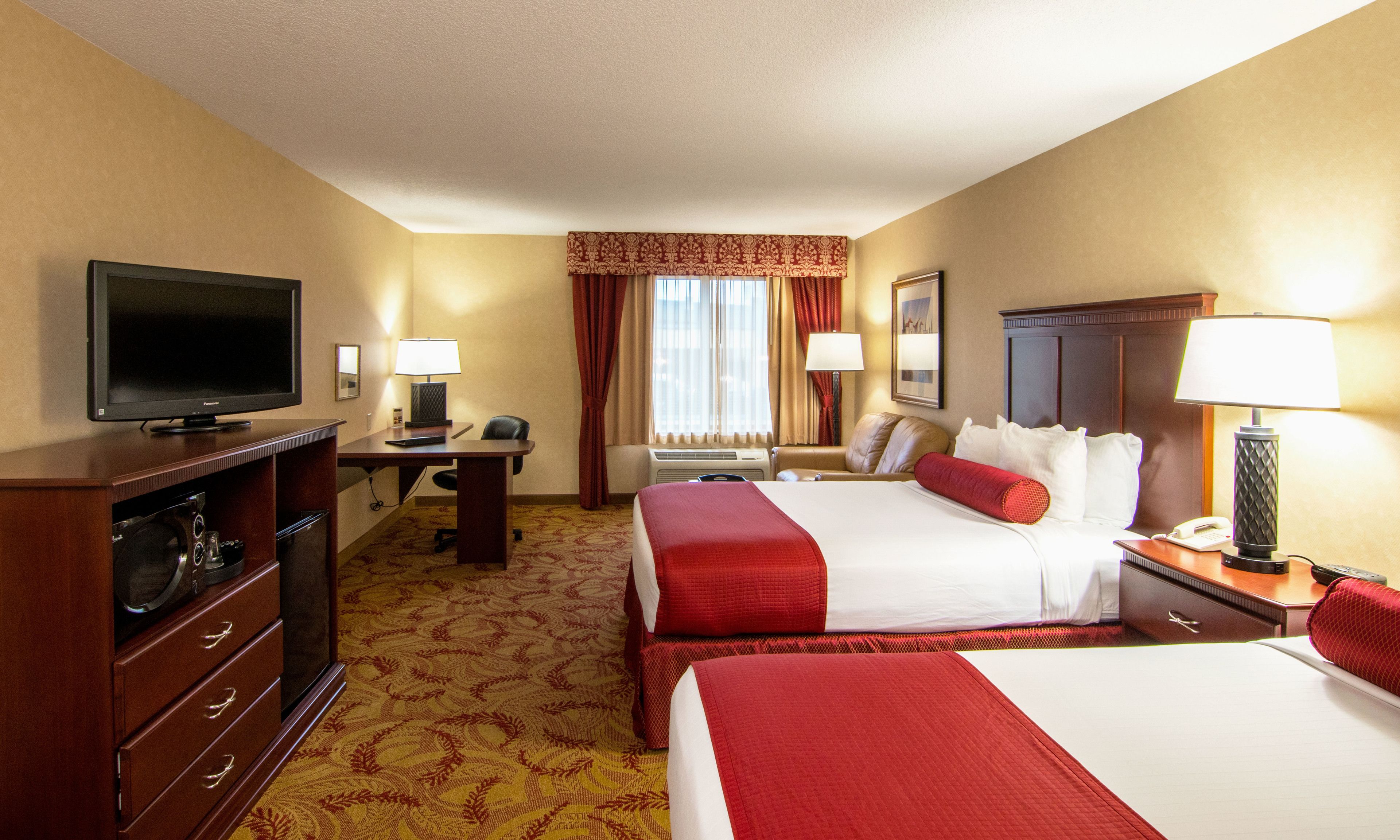 Quarto de hotel com duas camas, uma mesa, uma televisão e um telefone.