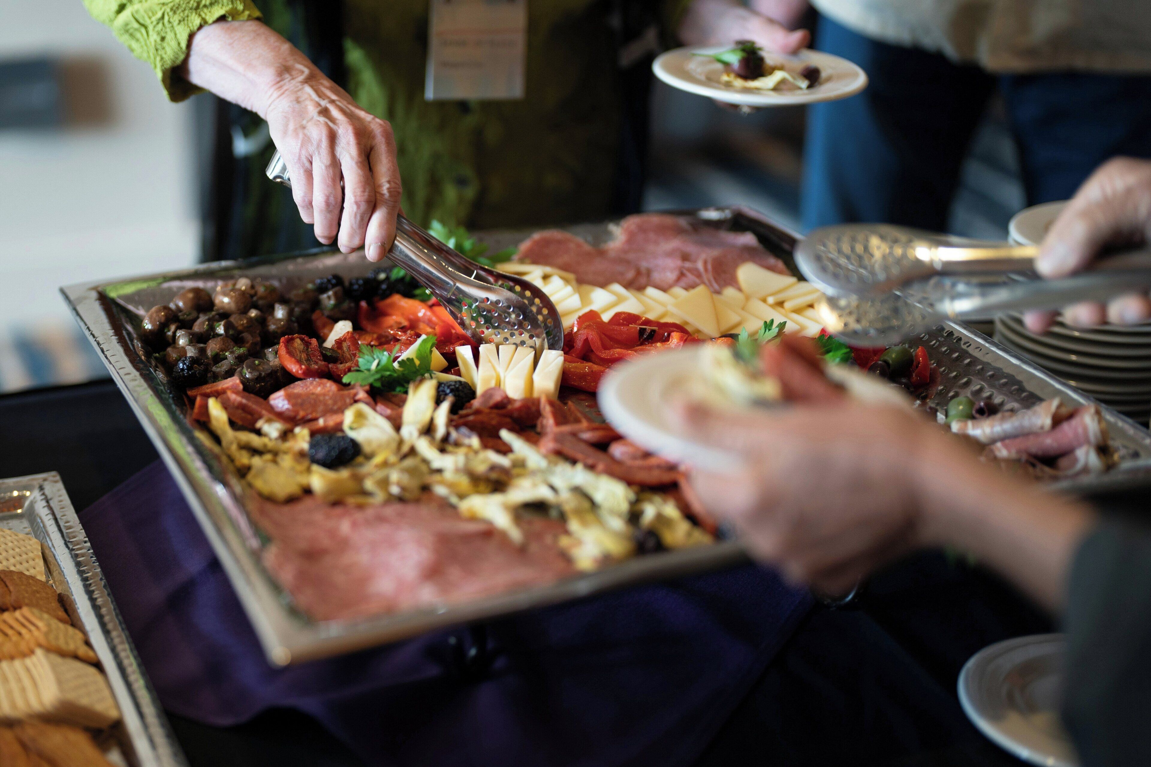 Un buffet proposant une variété de plats, notamment des viandes, des fromages et des légumes.