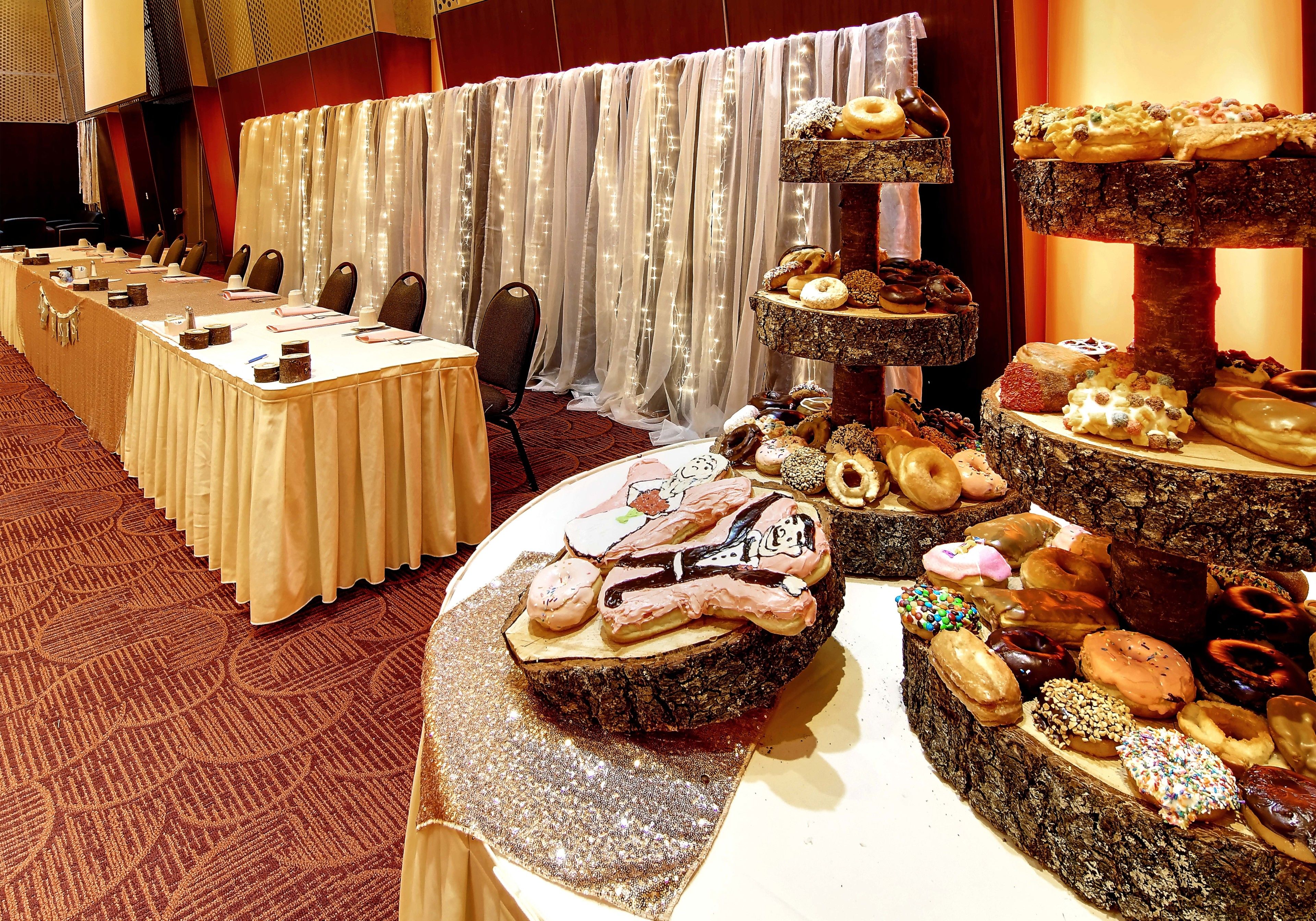 A conference room with a long table set for meetings, a tiered dessert display, and a curtain backdrop.