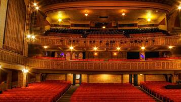 Een theater met meerdere balkons, rode zitplaatsen en versierde architectonische details.