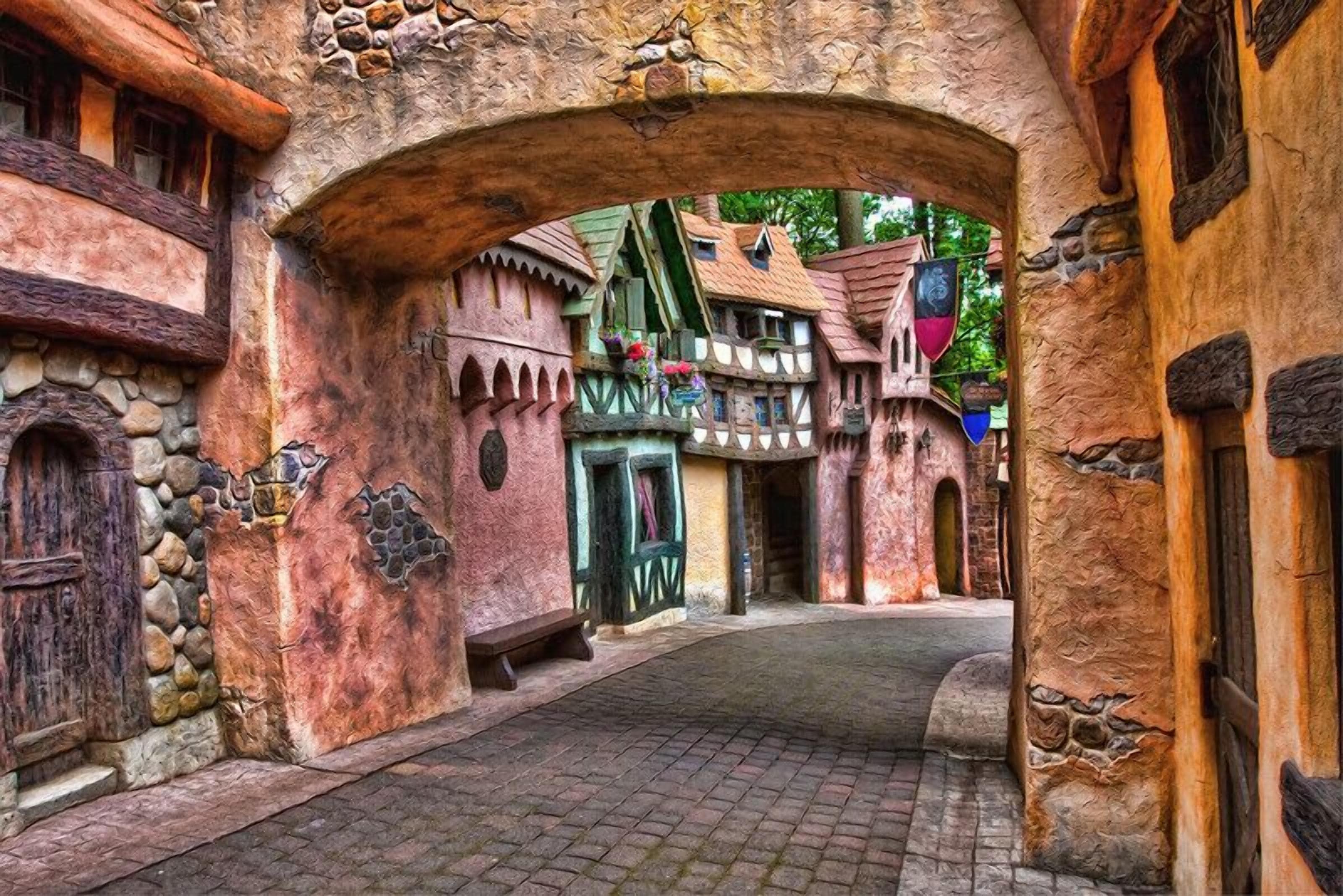 A narrow cobblestone street flanked by rustic buildings with stone walls and wooden shutters.
