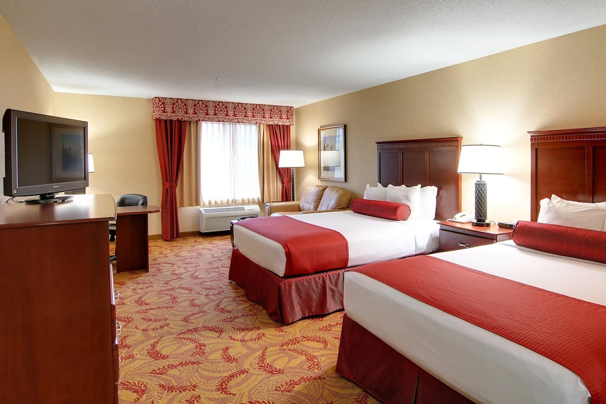 Une chambre d’hôtel avec deux lits, une télévision, un bureau et une chaise.