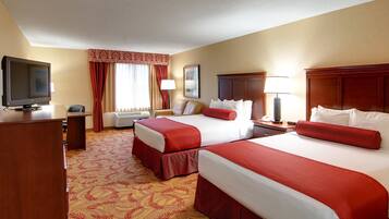 A hotel room with two beds, a TV, a desk, and a chair.