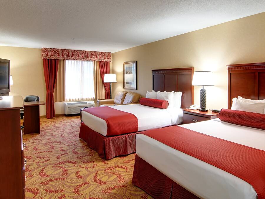 A hotel room with two beds, a TV, a desk, and a chair.