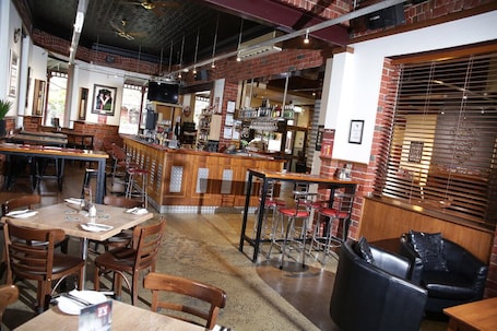 A restaurant with brick walls, wooden tables, and bar stools.