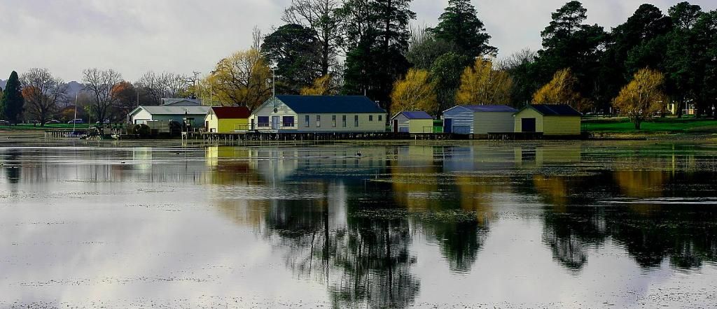 A waterfront property with multiple buildings, a calm lake, and trees in the background.