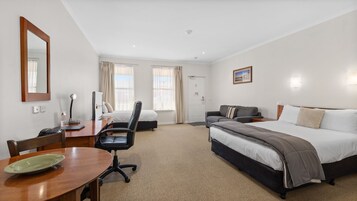 Una habitación de hotel con cama, escritorio con silla, sofá y mesa de comedor.