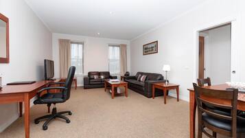 A furnished living room with a desk, office chair, two sofas, a coffee table, and a dining table with chairs.
