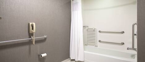 A bathroom with a toilet, a shower with a grab bar, and a towel rack.