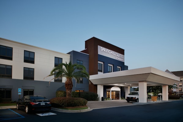 A hotel with a modern facade, a covered entrance, and a parking area.