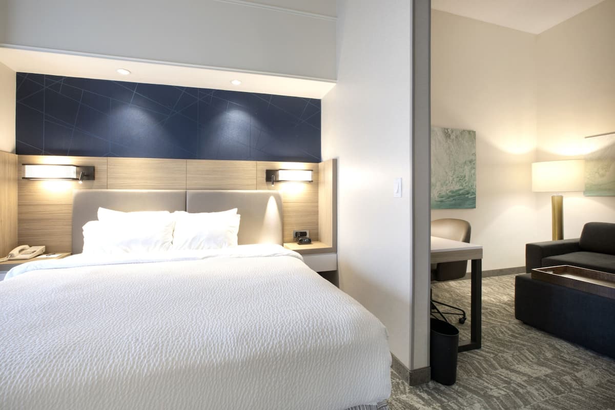 A modern hotel room with a large bed, bedside lamps, a desk, and a chair.
