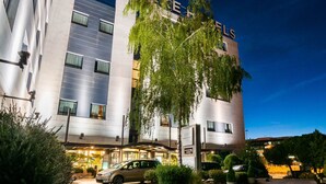A hotel with a modern facade, a parking area, and a well-lit entrance. - Exe Madrid Norte (Madrid)