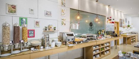 A hotel breakfast buffet with various food items, a coffee station, and a modern interior design.