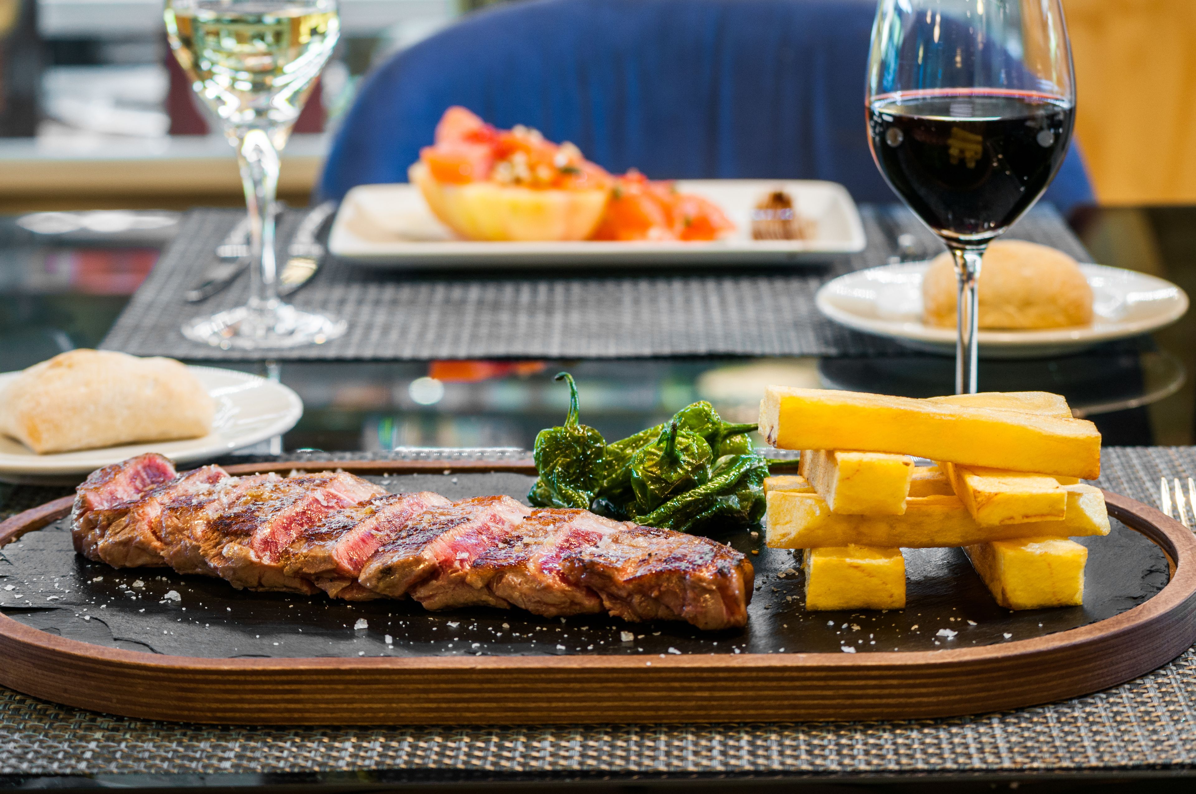 Une table à manger avec un steak, du fromage et des légumes.