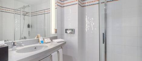 Un baño moderno con un espejo grande, un lavamanos y una cabina de ducha de vidrio.
