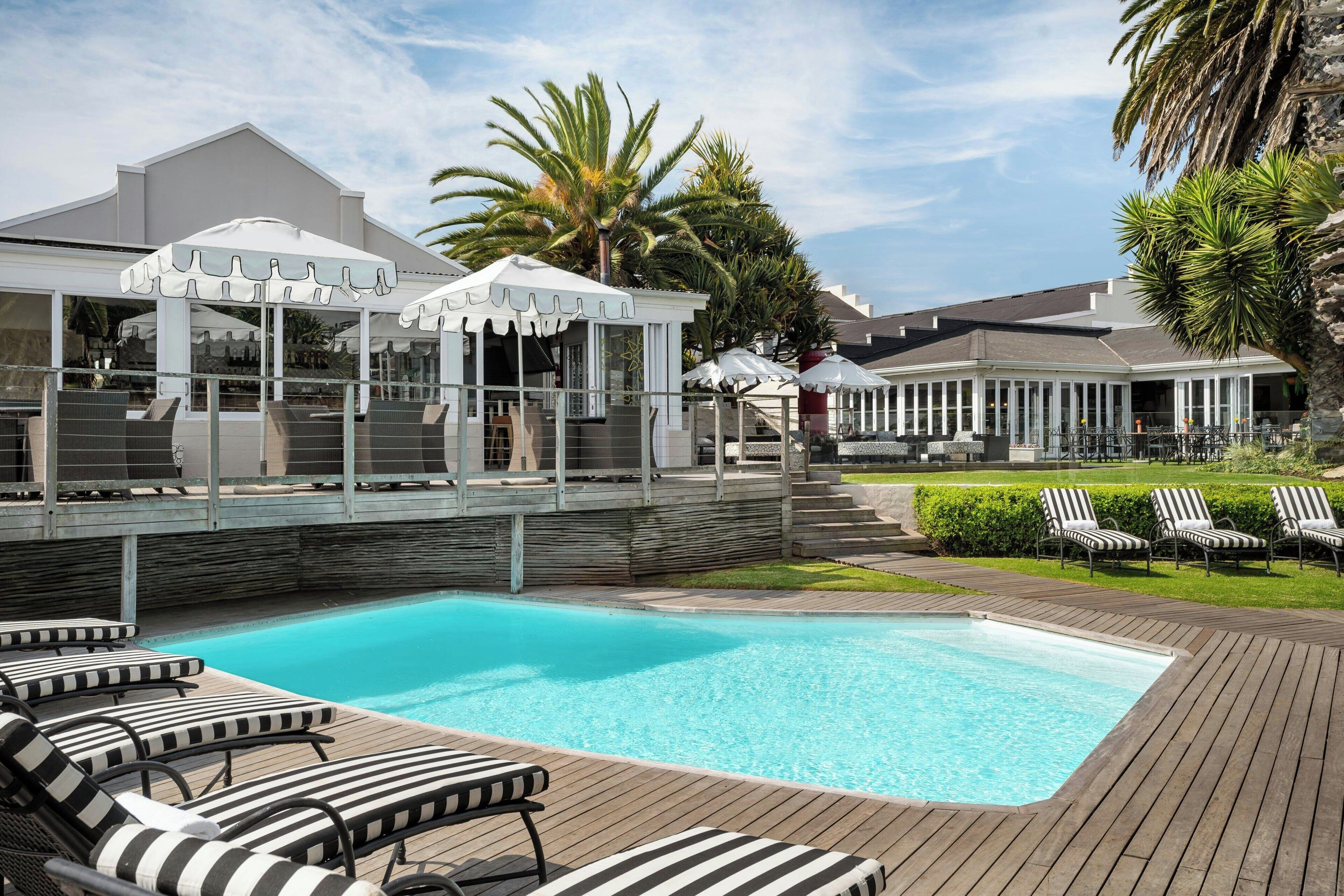 A pool area with lounge chairs, umbrellas, and a covered seating area.