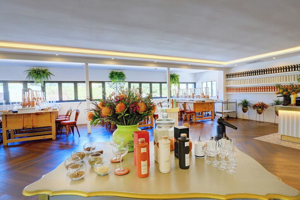 Un hall d’hôtel spacieux, avec une table centrale où sont exposés divers articles, notamment des bouteilles et des verres.