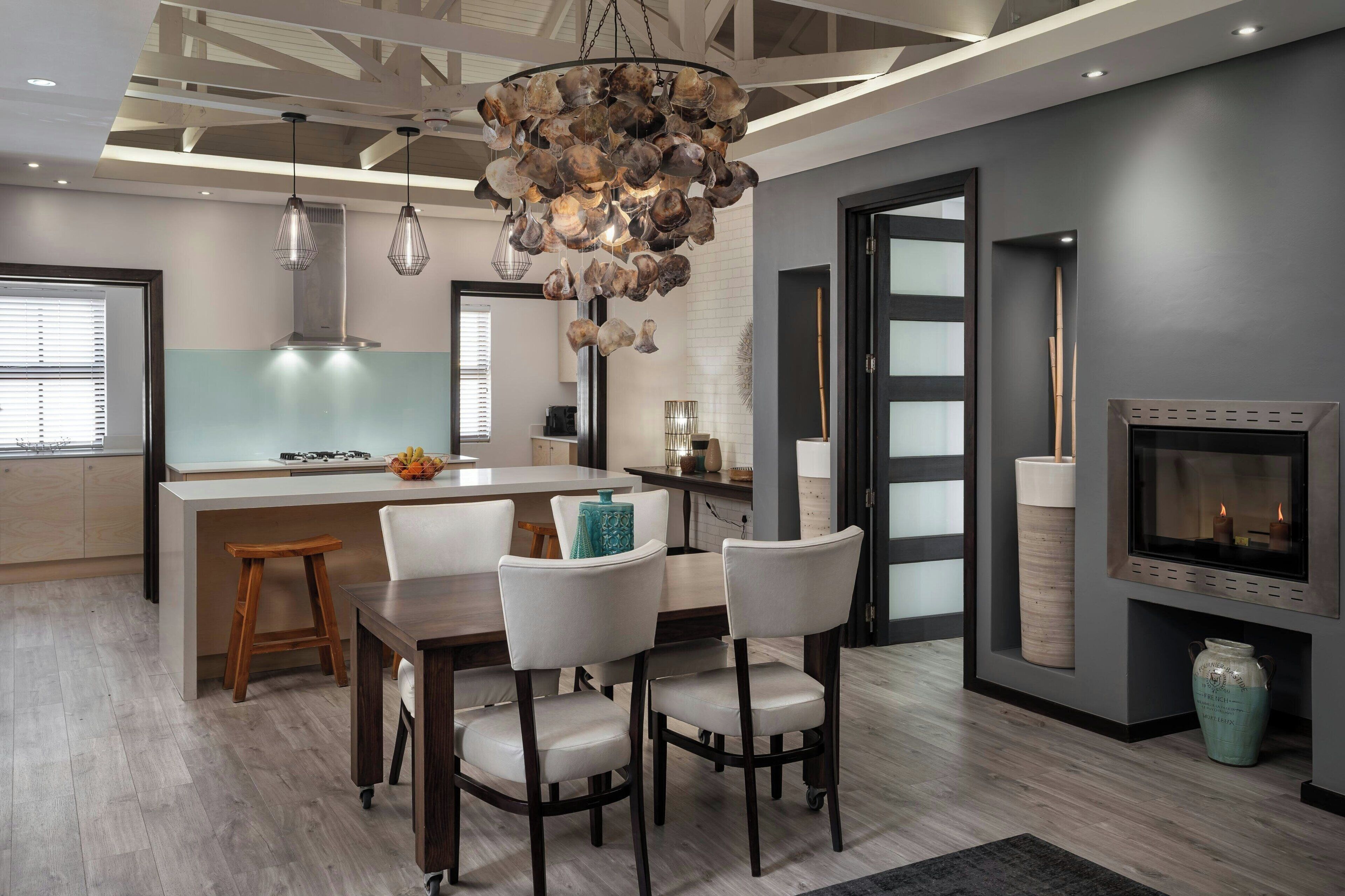 A modern kitchen with a central island, pendant lighting, and a built-in fireplace.