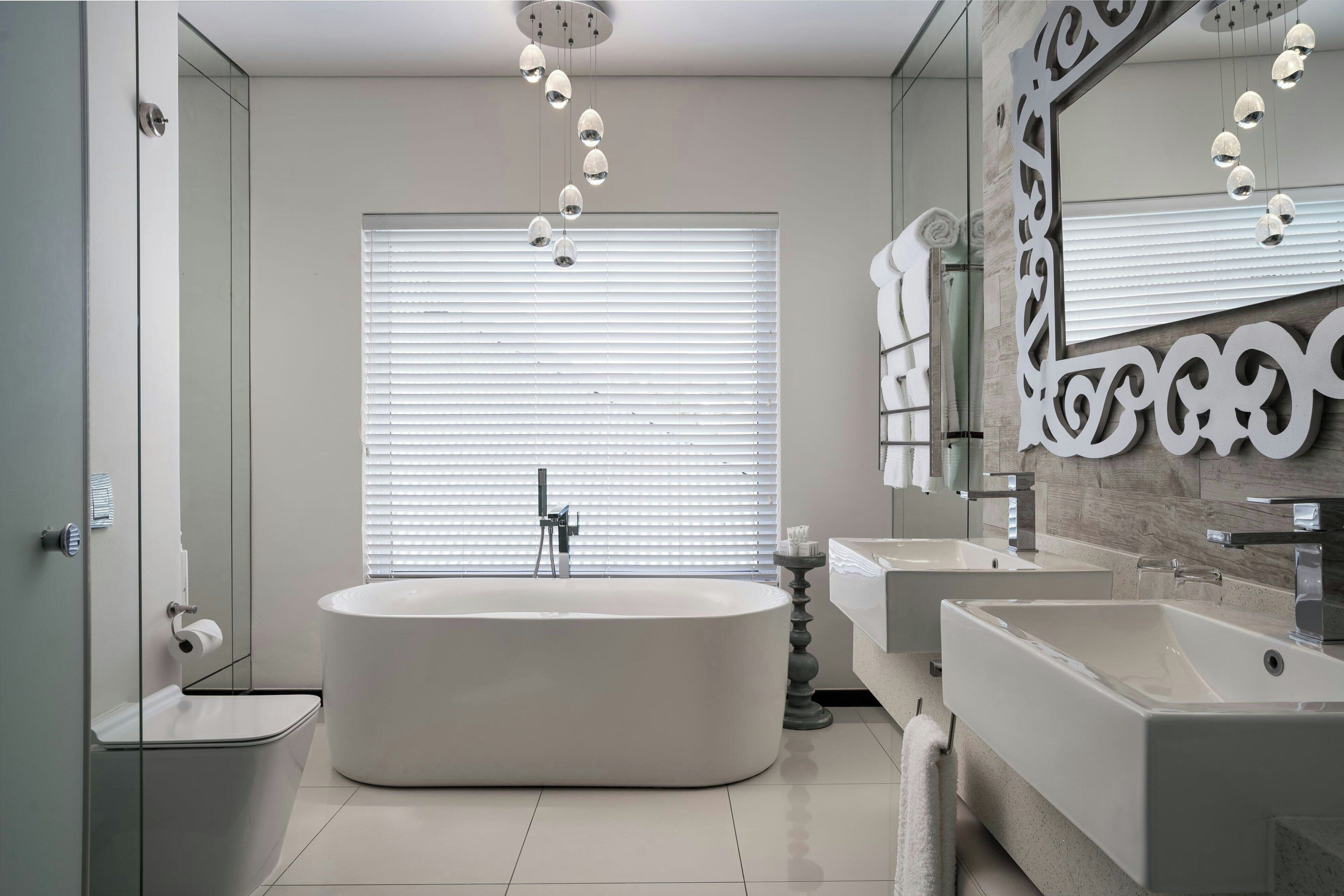 A modern bathroom with a freestanding bathtub, two sinks, and a large mirror.