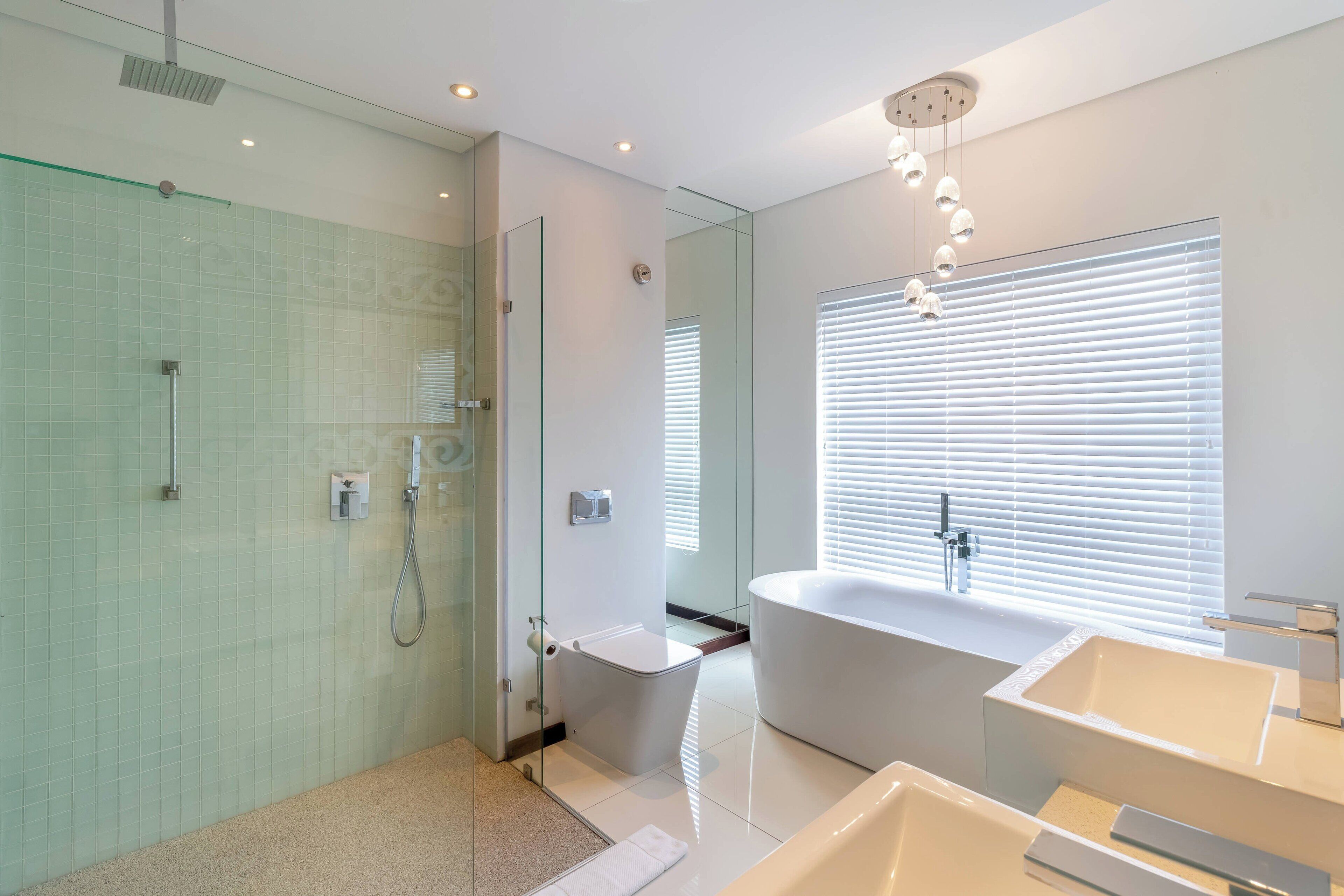 A modern bathroom with a glass-enclosed shower, a freestanding bathtub, and a large vanity with a sink.