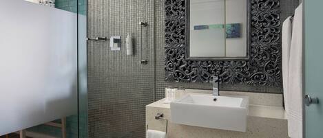Une salle de bain moderne avec une douche à parois de verre, un lavabo blanc et un miroir décoratif.