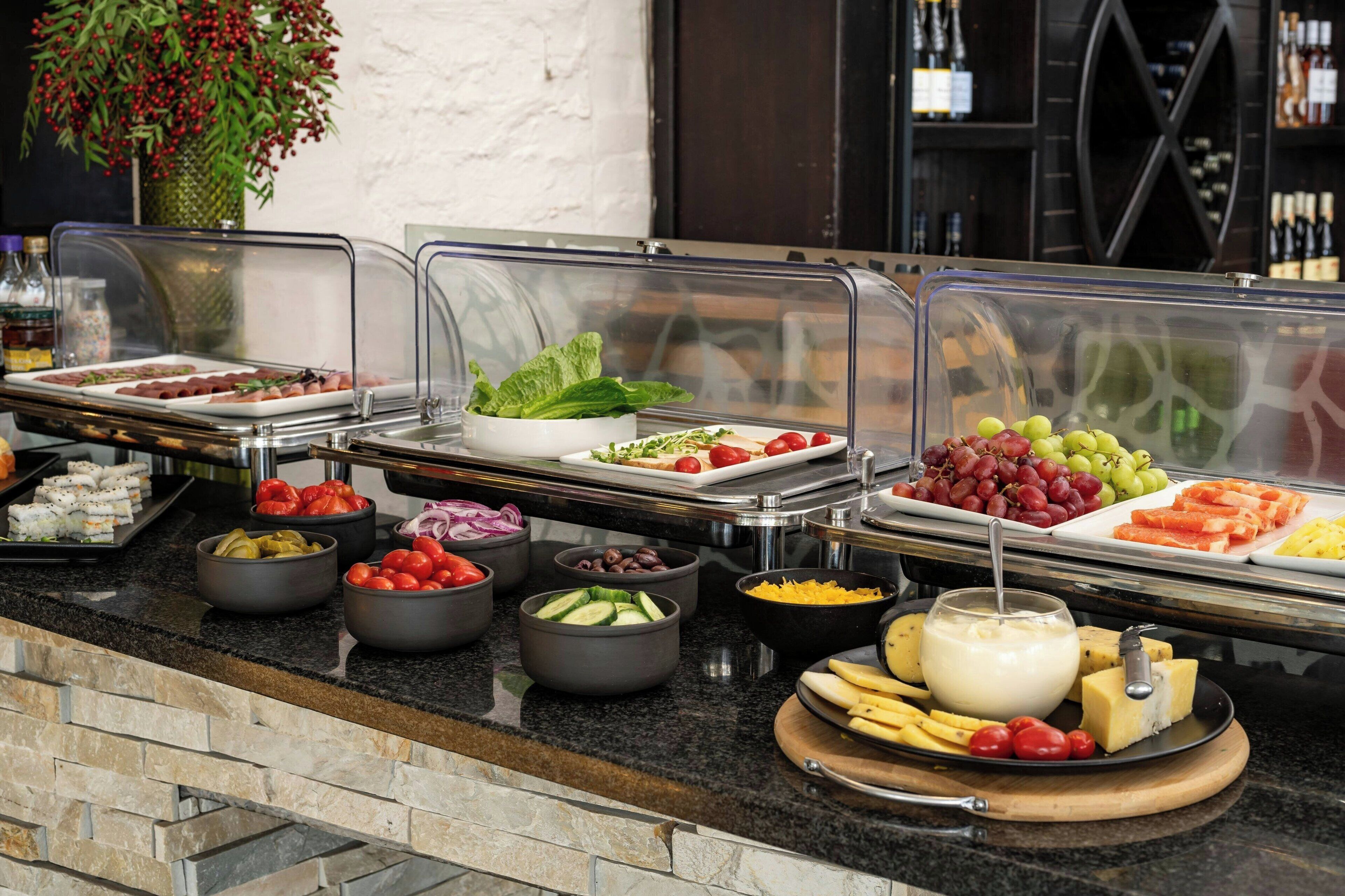 A buffet with various food items including salads, fruits, cheeses, and dips.