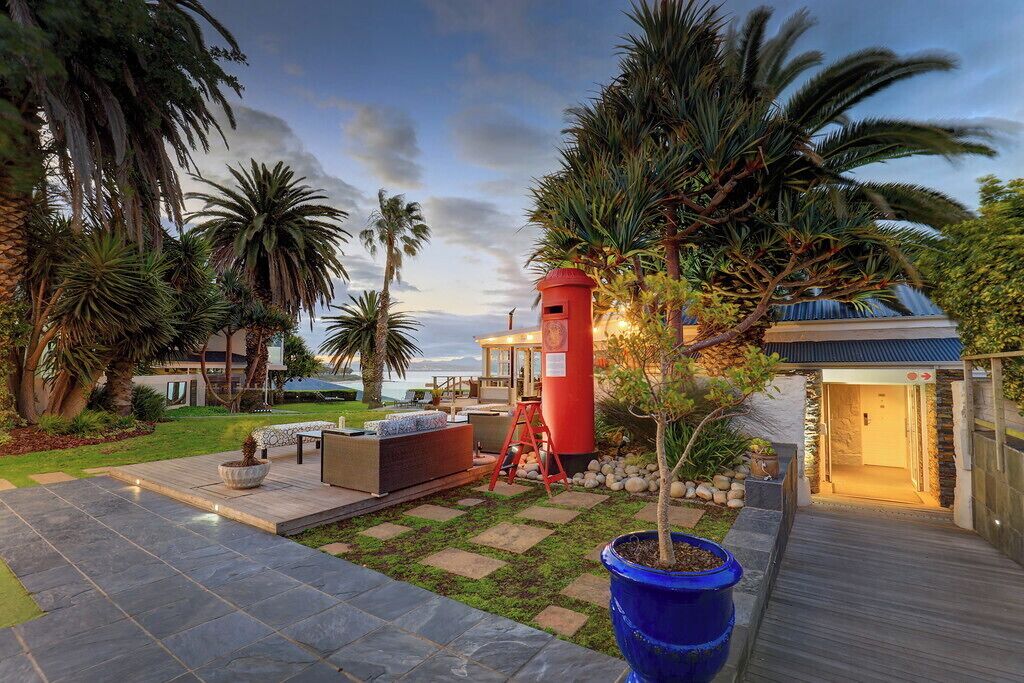 A modern outdoor patio area with a stone pathway, seating, and a red lighthouse structure.