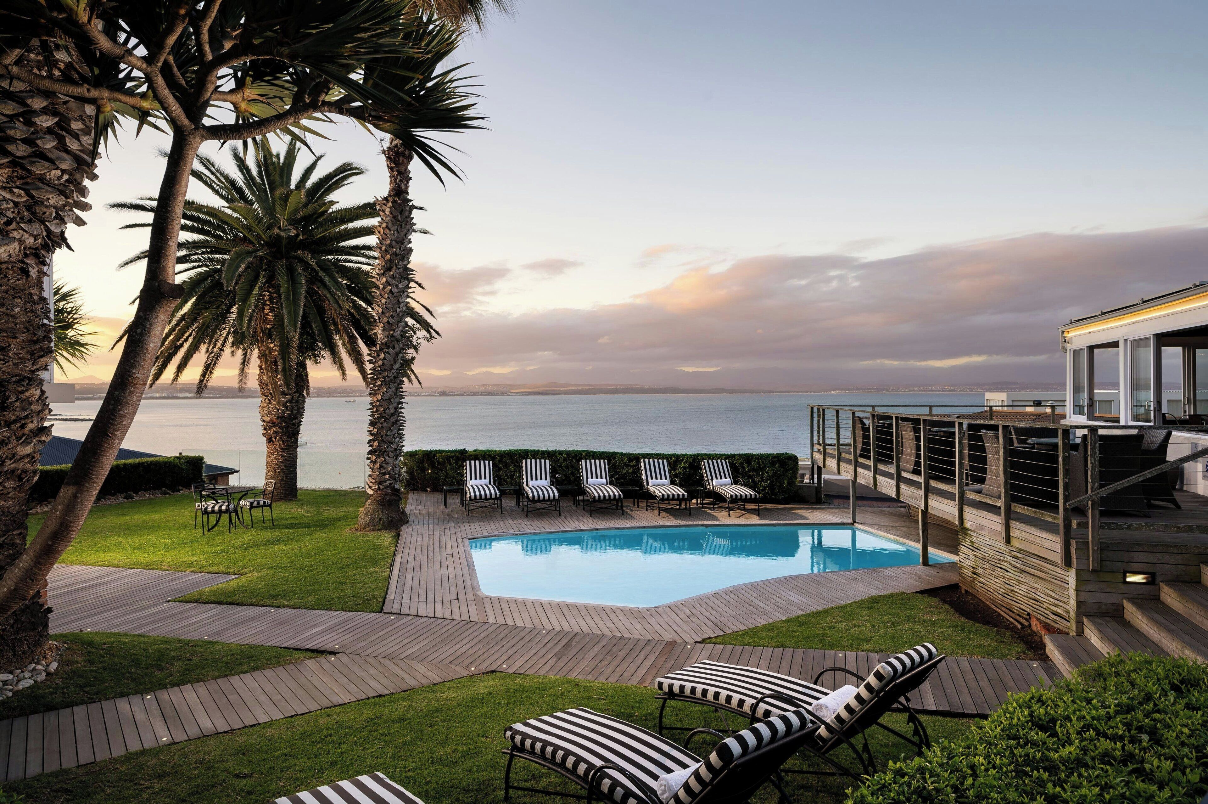 Ein Poolbereich mit Liegestühlen und Blick aufs Meer.