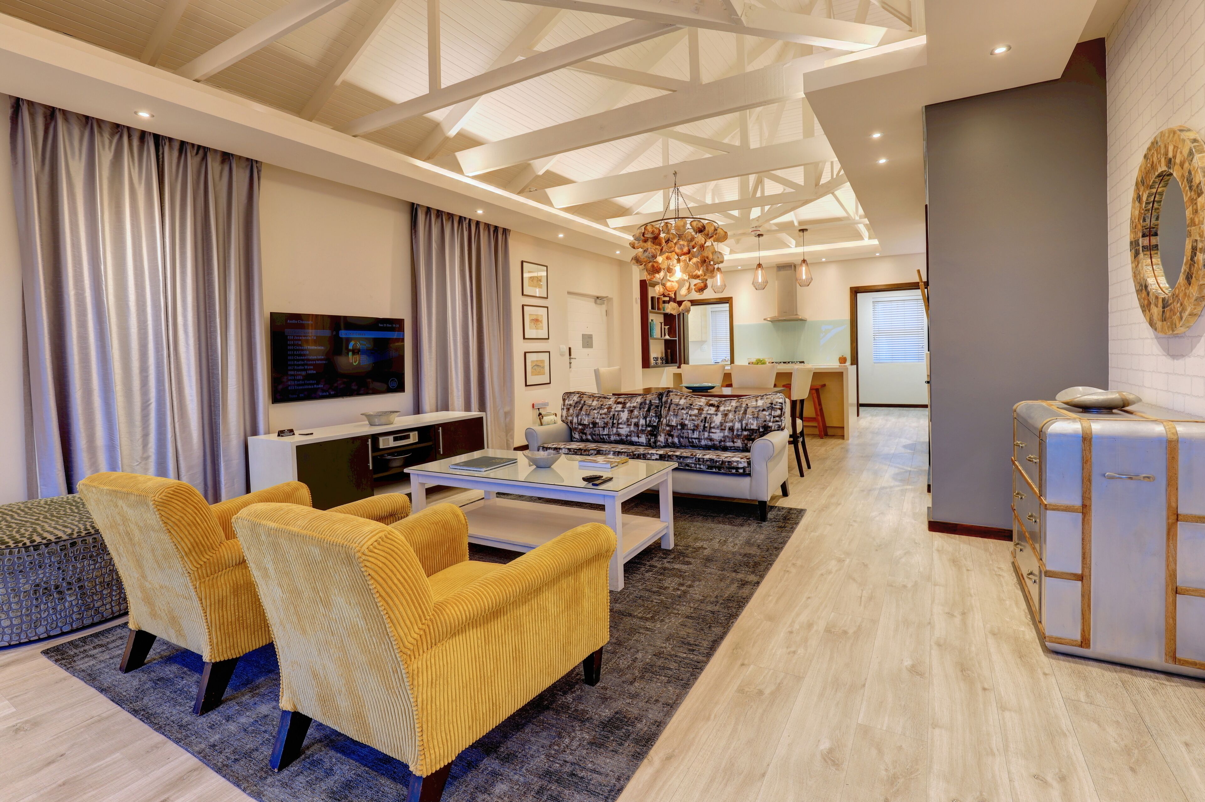 A modern living room with a sofa, yellow chairs, a coffee table, and a TV.
