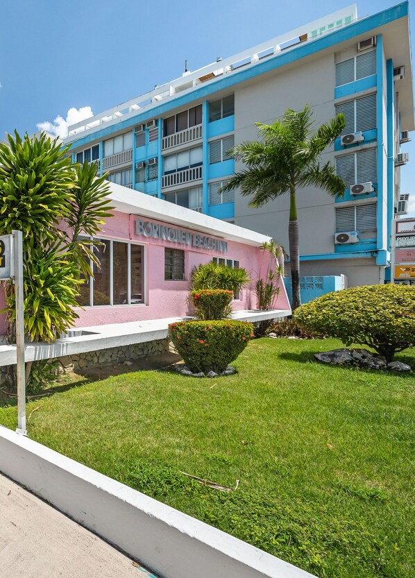 A hotel with a pink facade, multiple balconies, and air conditioning units. - Borinquen Beach Inn (Carolina)