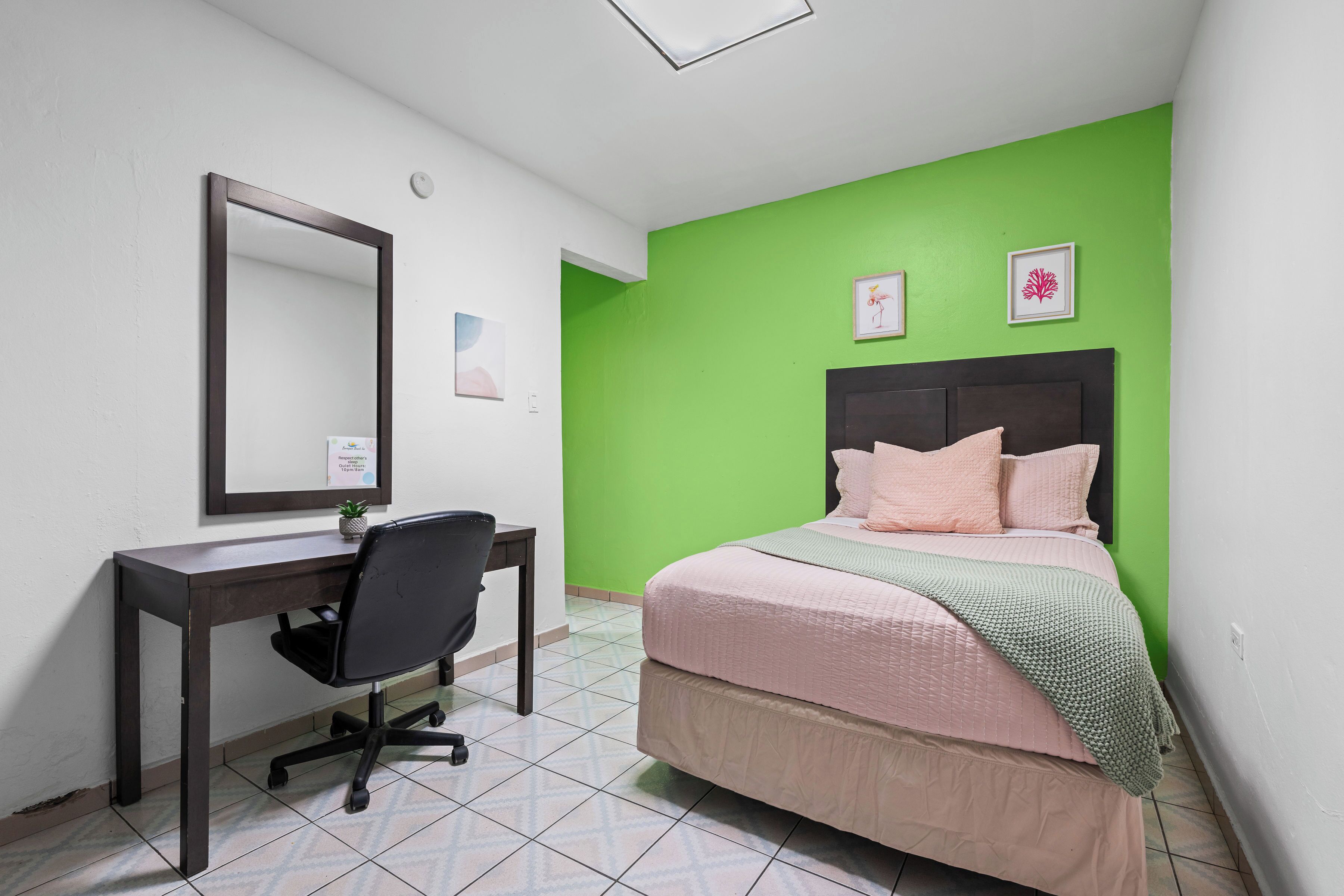 A bedroom with a bed, a desk, and a chair.