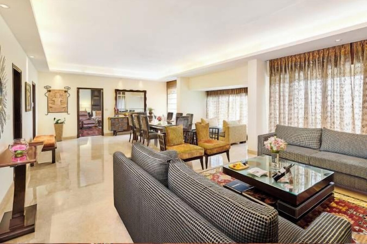 A spacious living room with a sofa set, a coffee table, and a dining area with chairs and a table.