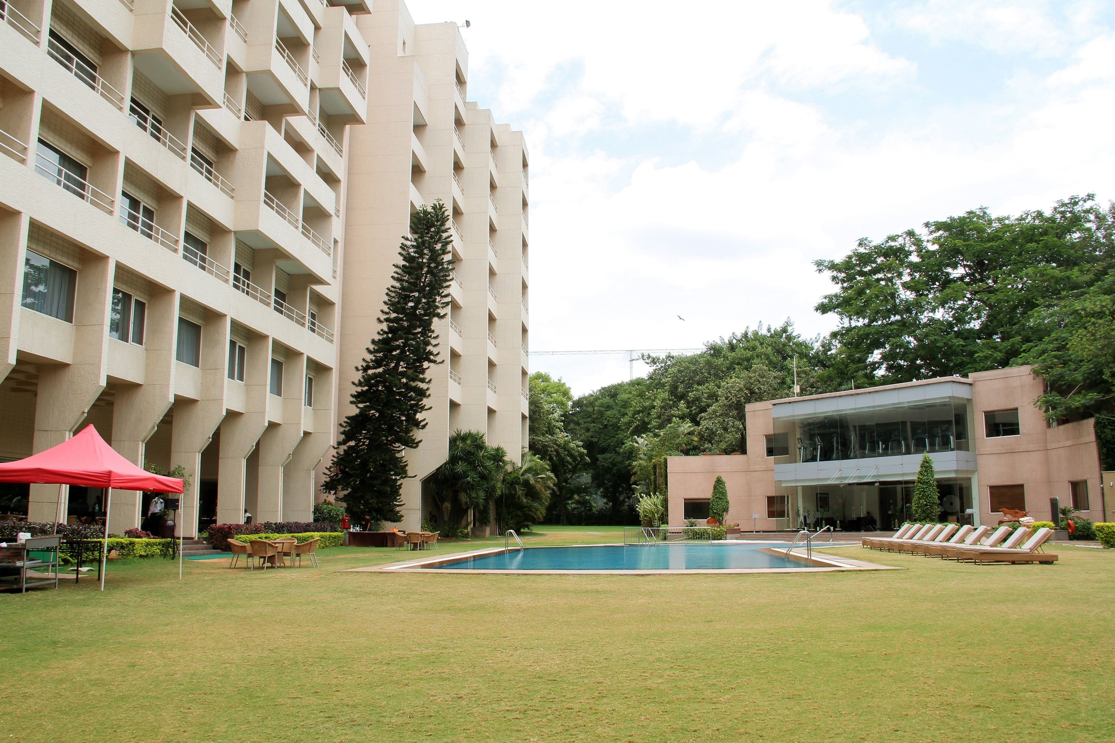 Un hotel con piscina, mobiliario exterior y un edificio grande con balcones.