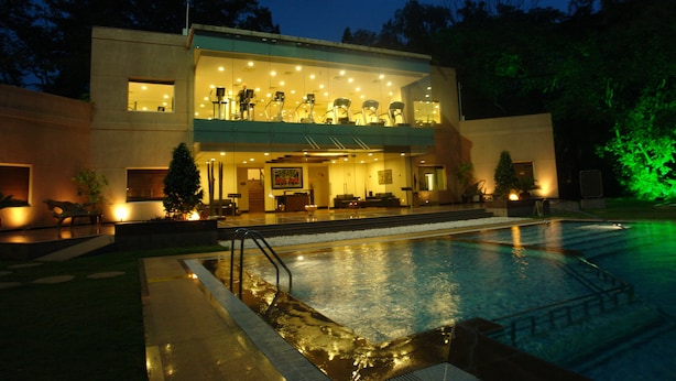 Un hotel moderno con piscina, un área exterior cubierta e iluminación en la entrada.