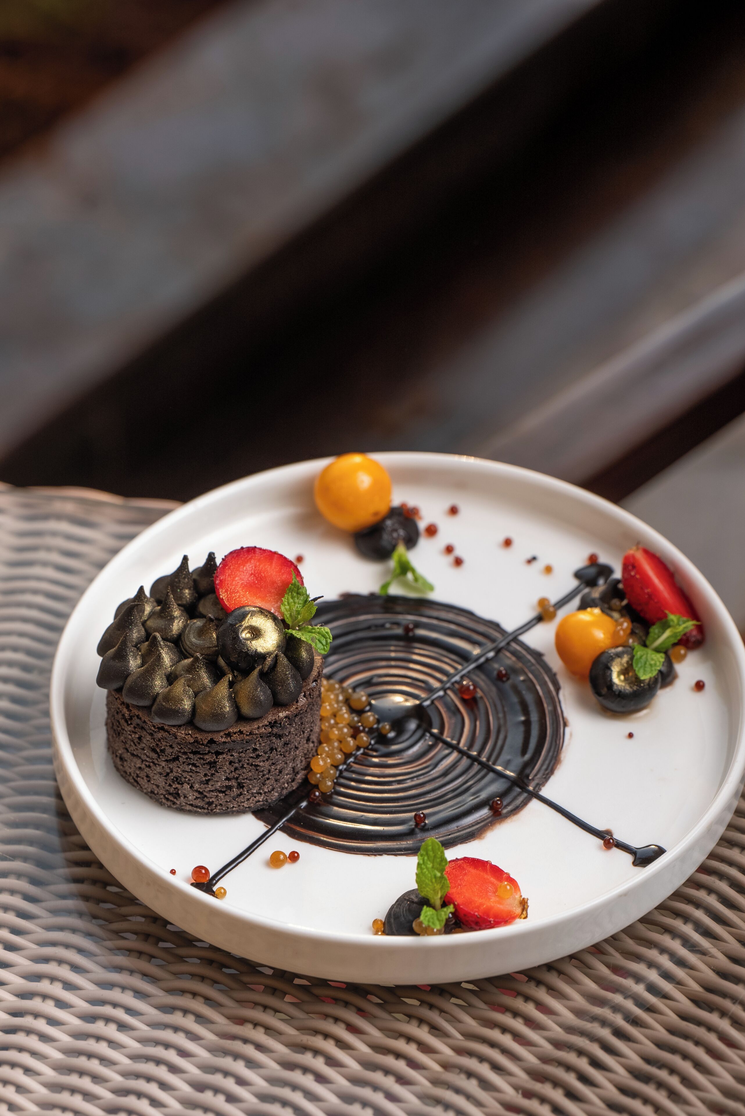 Un postre en un plato blanco con pastel de chocolate, fresas y bayas.