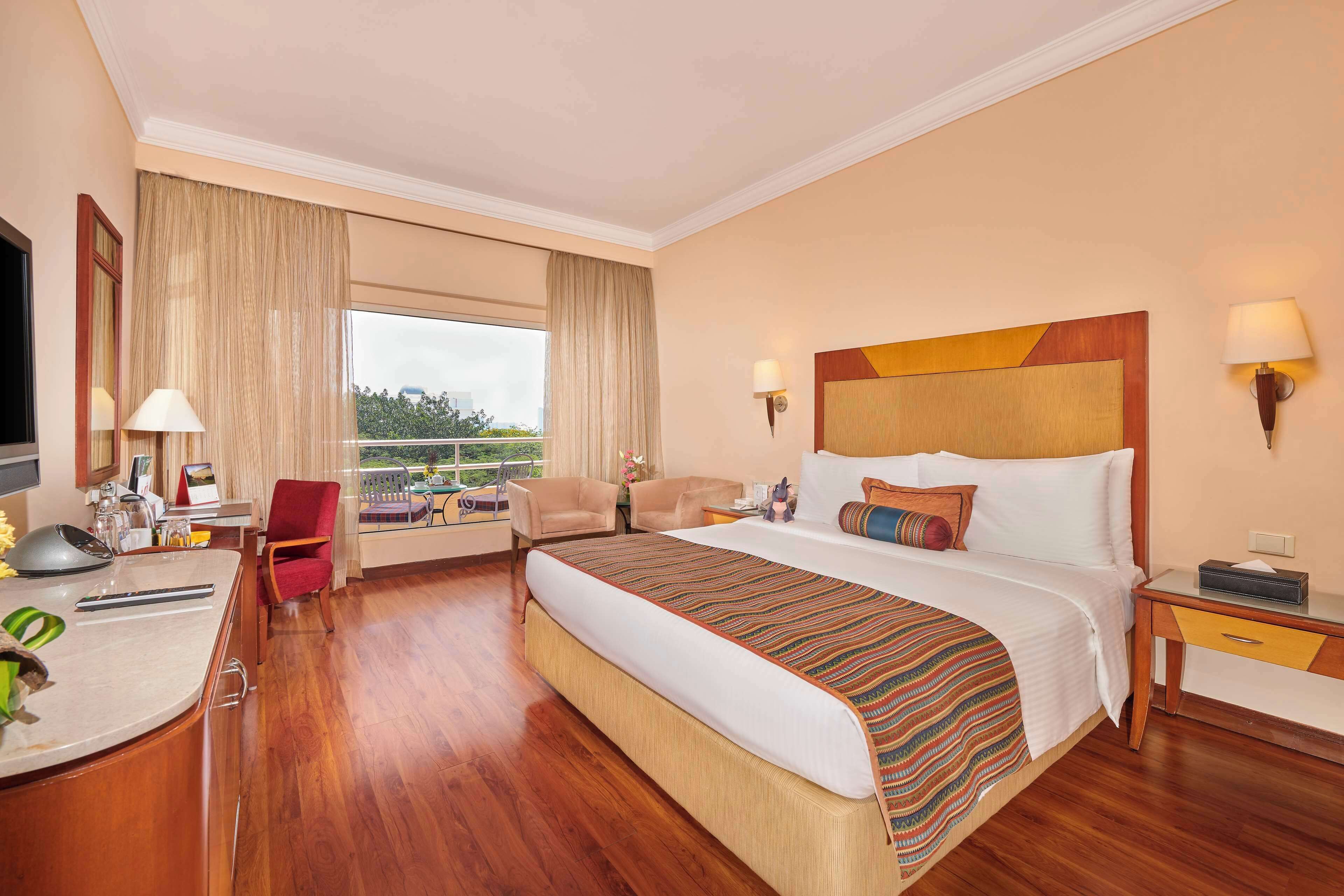 A hotel room with a large bed, a desk with a computer, a chair, and a view of the outdoors.