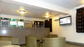A lobby with wicker chairs, a bar area with bottles, and a television screen. - Stop Over Motels (Lagos)