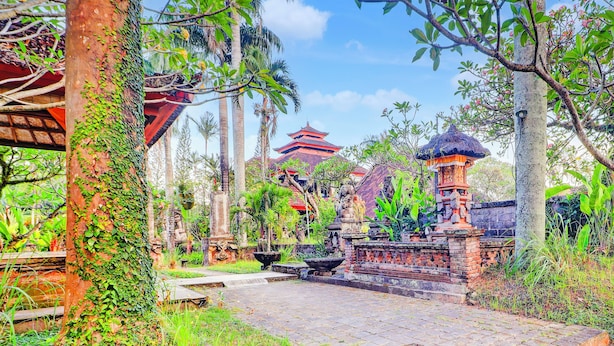 A traditional temple with a red roof, surrounded by lush greenery and stone pathways. - Collection O Ubud Near Central Ubud Formerly Hotel Suly (Ubud)
