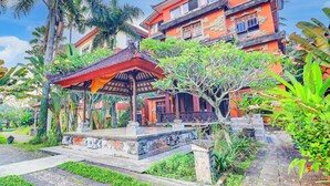 A traditional building with a red facade, a covered pavilion, and lush greenery. - Collection O Ubud Near Central Ubud Formerly Hotel Suly (Ubud)